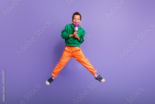 Photo of cheerful crazy boy wear green stylish clothes speak microphone have fun entertainment isolated on purple color background