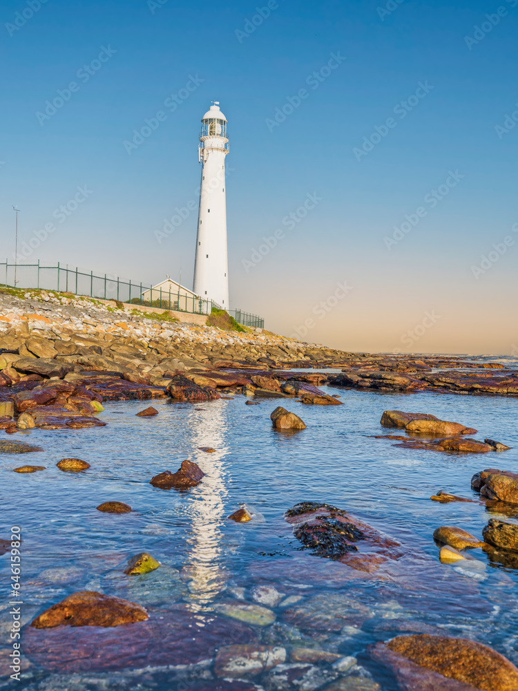 Obraz premium Slangkop Lighthouse and its reflection in the sea water during a clear afternoon, Kommetjie, Cape Town, South Africa