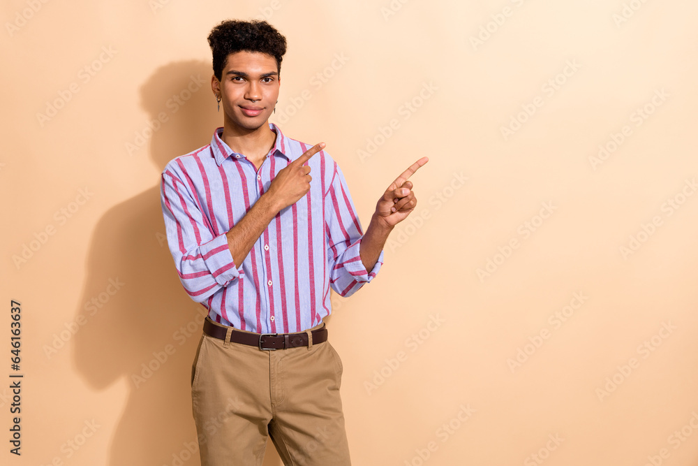 Photo of young office manager guy direct fingers empty space corporate announce isolated pastel beige color background Photo of young office manager guy direct fingers empty space corporate announce isolated pastel beige color background