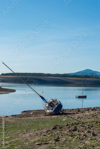 Abandoned sailboat on the water is edge low water level due to drought in vertical