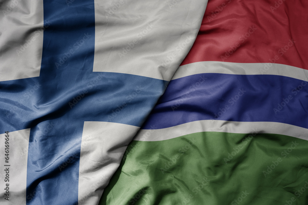 Obraz premium big waving national colorful flag of finland and national flag of gambia .
