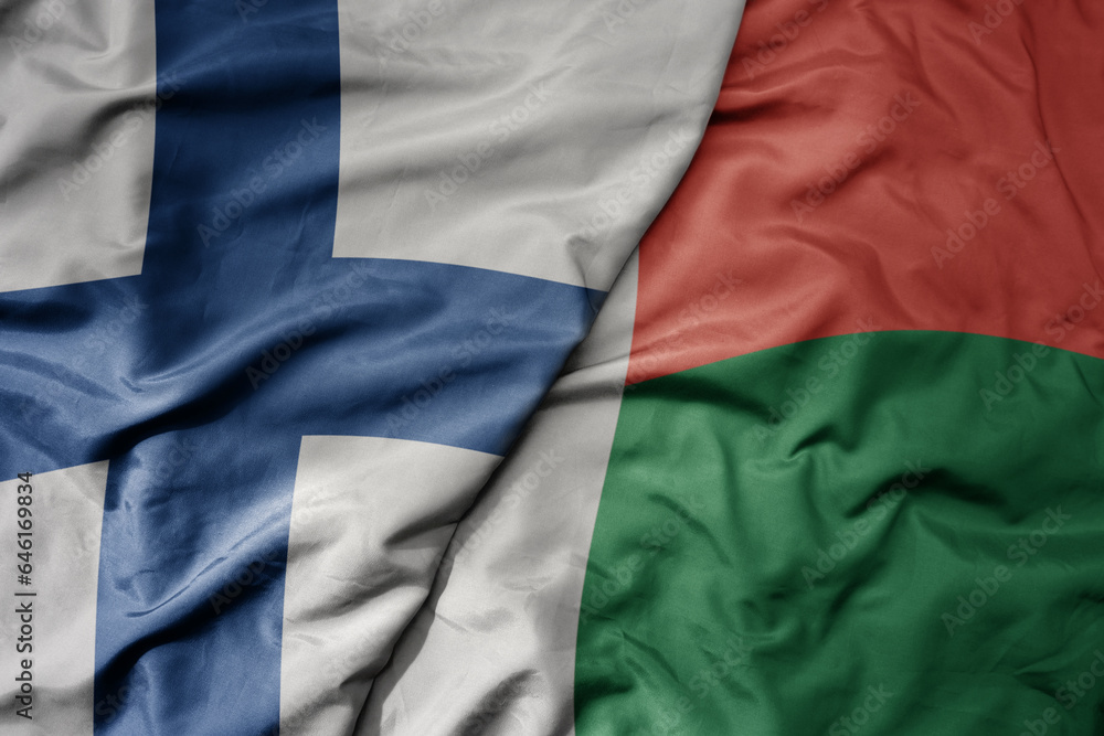 big waving national colorful flag of finland and national flag of madagascar .