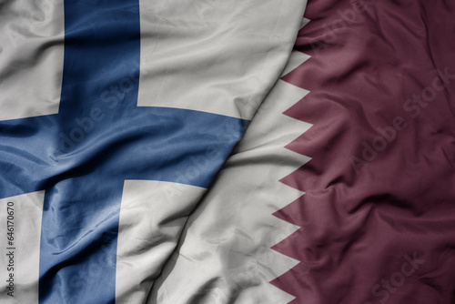 big waving national colorful flag of finland and national flag of qatar .