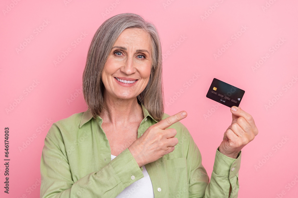 Photo of retired businesswoman banker directing finger plastic payment card salary send profit wireless isolated on pink color background Photo of retired businesswoman banker directing finger plastic payment card salary send profit wireless isolated on pink color background