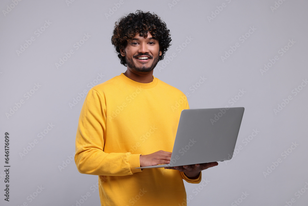 Smiling man with laptop on light grey background Smiling man with laptop on light grey background