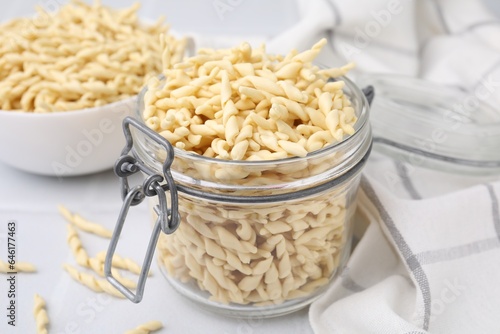 Uncooked trofie pasta on white table, closeup photo