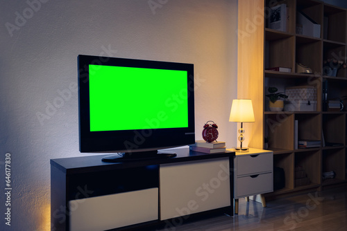 4K LCD TV with green chroma key on cabinet in the living room, white table and lamps indoors. Cozy living room, interior design © Pituk
