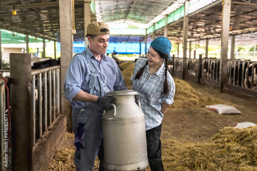 Caucasian cowman and cow girl holding milk container working in dairy farm