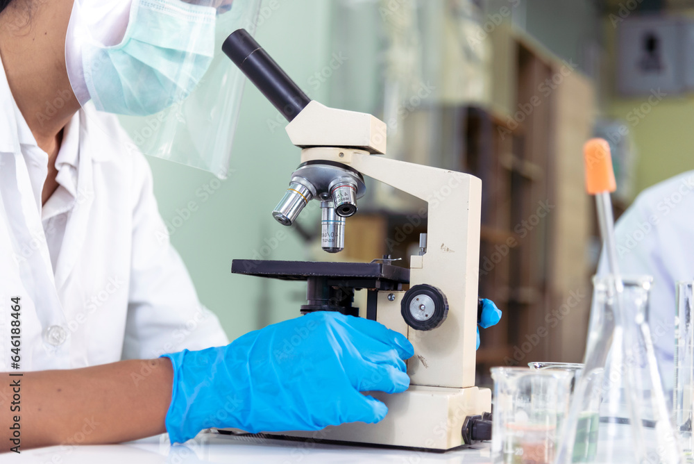 Scientist man look into Microscope research in science laboratory. Asian scientist looking equipment laboratory chemistry labs. Covid-19 coronavirus biochemistry research experiment vaccine concept Scientist man look into Microscope research in science laboratory. Asian scientist looking equipment laboratory chemistry labs. Covid-19 coronavirus biochemistry research experiment vaccine concept