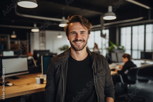 Smiling portrait of a happy young caucasian man working for a modern startup company in a business office © Baba Images