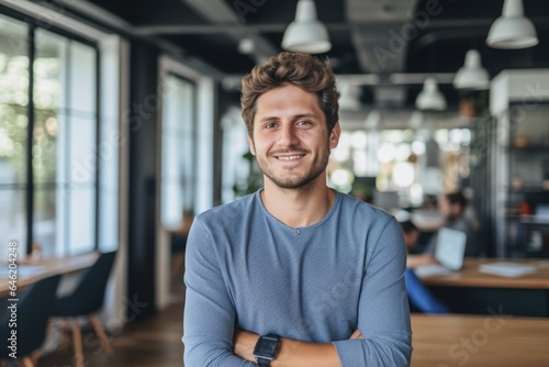 Smiling portrait of a happy young caucasian man working for a modern startup company in a business office