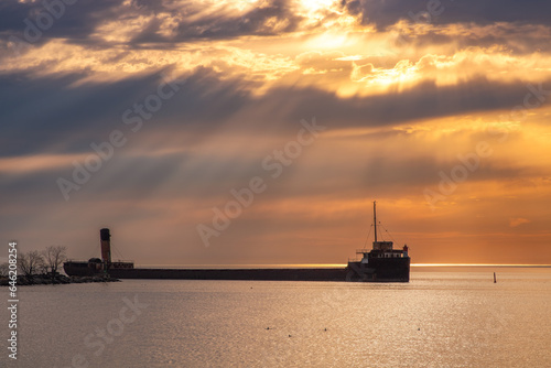 Photography Vibrant sunrise with sun rays over a long freighter ship pier