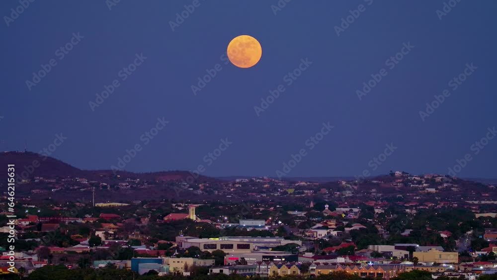 Pan up across curacao container industrial port zone terminal to red orange supermoon above city of willemstad