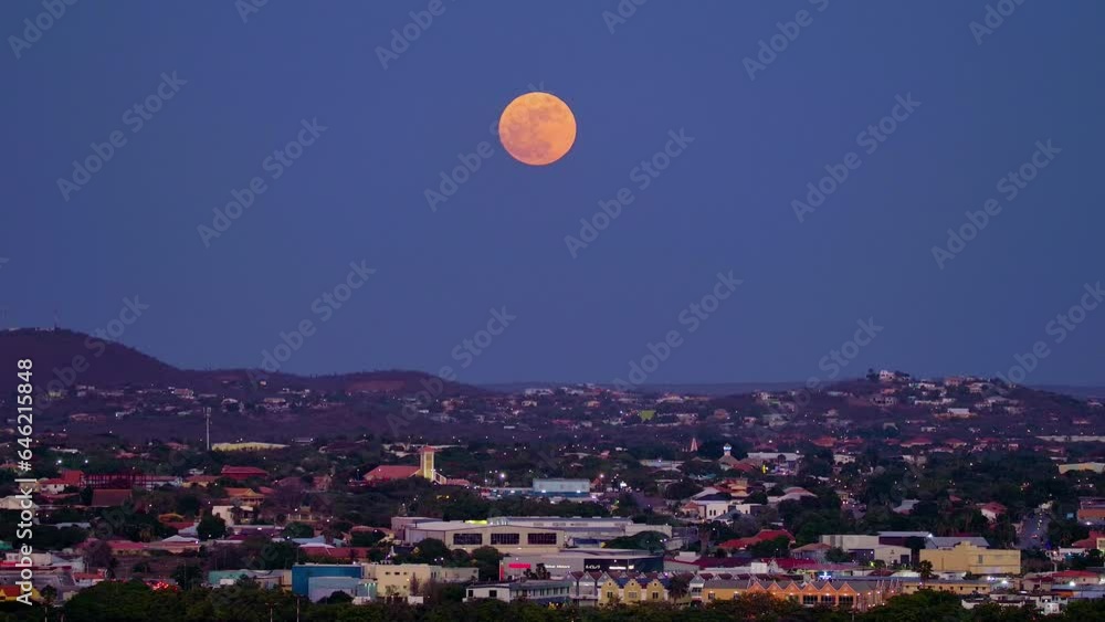 Pan across willemstad curacao city at dusk as rare full blue supermoon rises red against purple sky Pan across willemstad curacao city at dusk as rare full blue supermoon rises red against purple sky