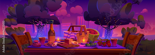 Romantic date or picnic evening in city park. Cartoon table with snacks and fruits, bottle of wine, wicker basket and candles in garden with multistory building cityscape. Night outside rest.