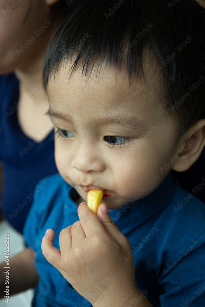 Happy mother and Asian kid eating French Fries together Happy mother and Asian kid eating French Fries together