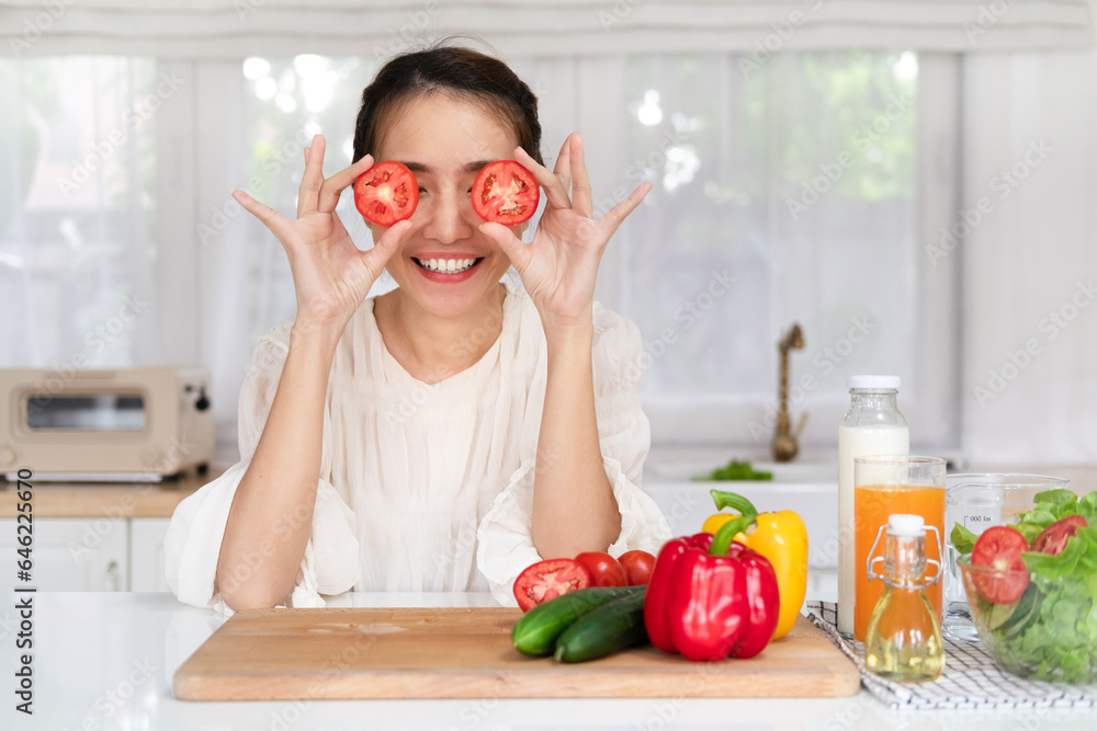 Happy young latin lady having fun and covering eyes with tomato halves, fooling around in kitchen interior, looking and smiling at camera while cooking dinner Happy young latin lady having fun and covering eyes with tomato halves, fooling around in kitchen interior, looking and smiling at camera while cooking dinner