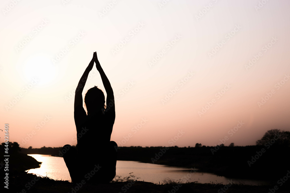 Silhouette of woman praying over beautiful sky background

