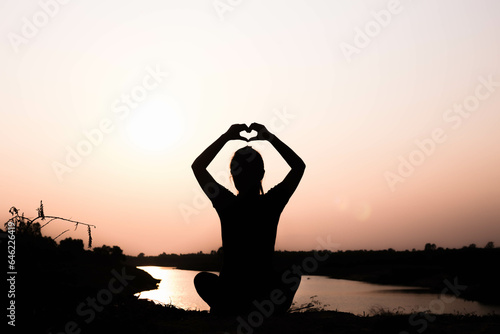 Silhouette of woman praying over beautiful sky background 