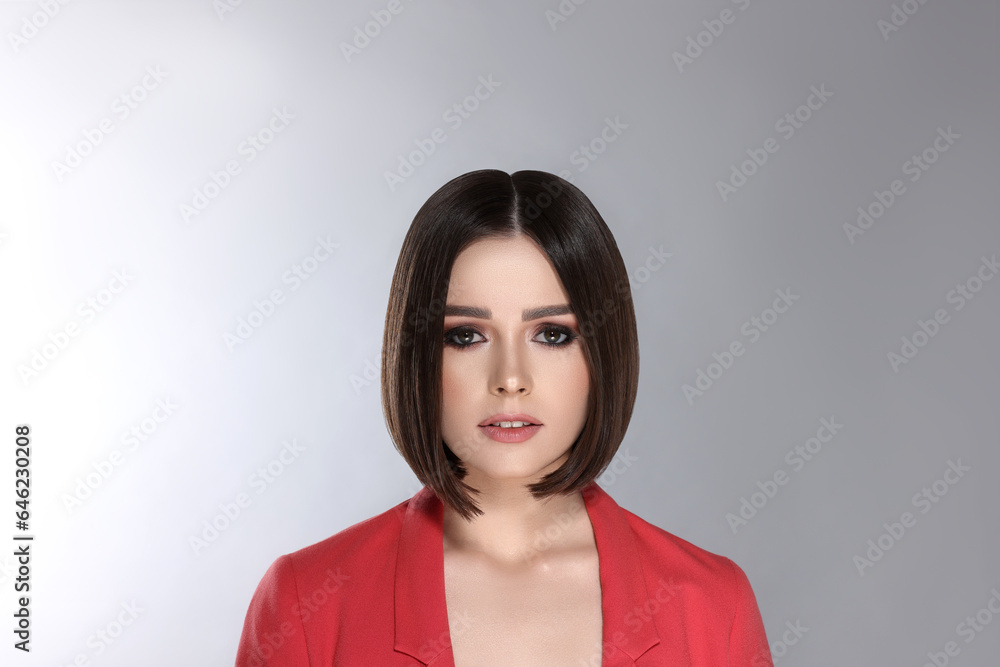 Portrait of stylish young woman with brown hair on grey background Portrait of stylish young woman with brown hair on grey background