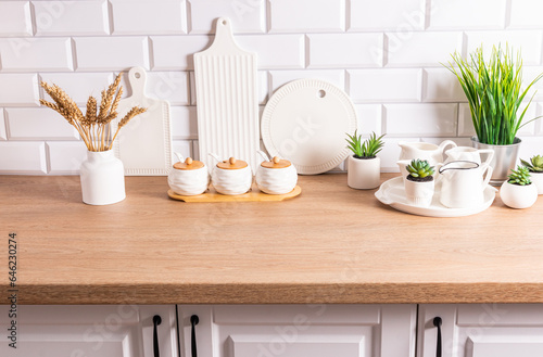 White kitchen utensils, cutting ceramic boards and dishes, a vase with ears of corn in the interior of a modern kitchen in white tones. © Marina