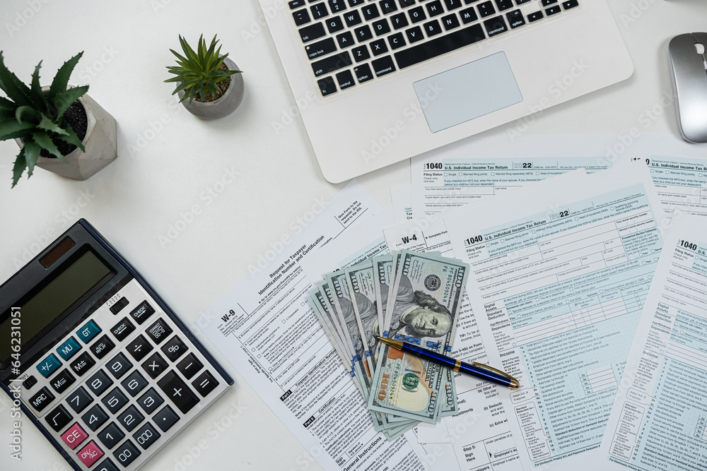 Deadline concept 1040 tax form with laptop calculator and dollar bills on office desk Deadline concept 1040 tax form with laptop calculator and dollar bills on office desk