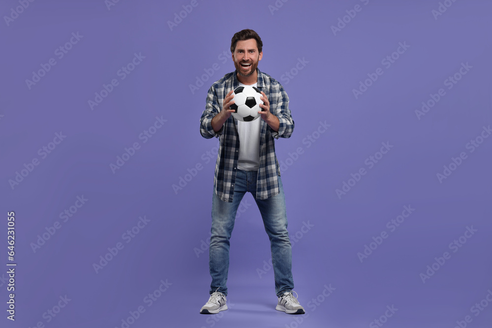 Emotional sports fan with soccer ball on purple background Emotional sports fan with soccer ball on purple background