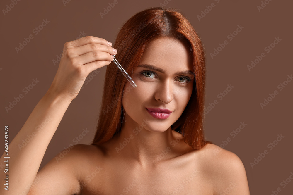 Beautiful young woman applying cosmetic serum onto her face on brown background Beautiful young woman applying cosmetic serum onto her face on brown background