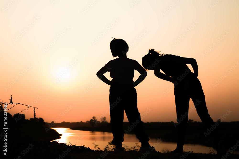 Naklejka premium Silhouette of a family comprising a father, mother and two children happy family the sunset.Concept of friendly 