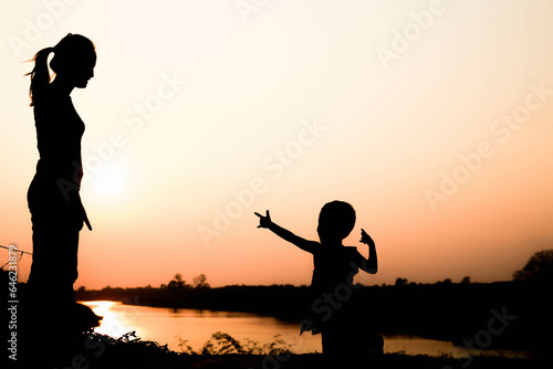 Silhouette of a family comprising a father  mother and two children happy family the sunset.Concept of friendly 