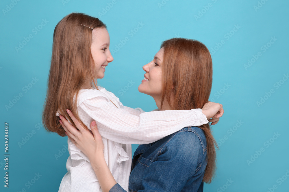 Portrait of happy mother and her cute daughter on light blue background Portrait of happy mother and her cute daughter on light blue background