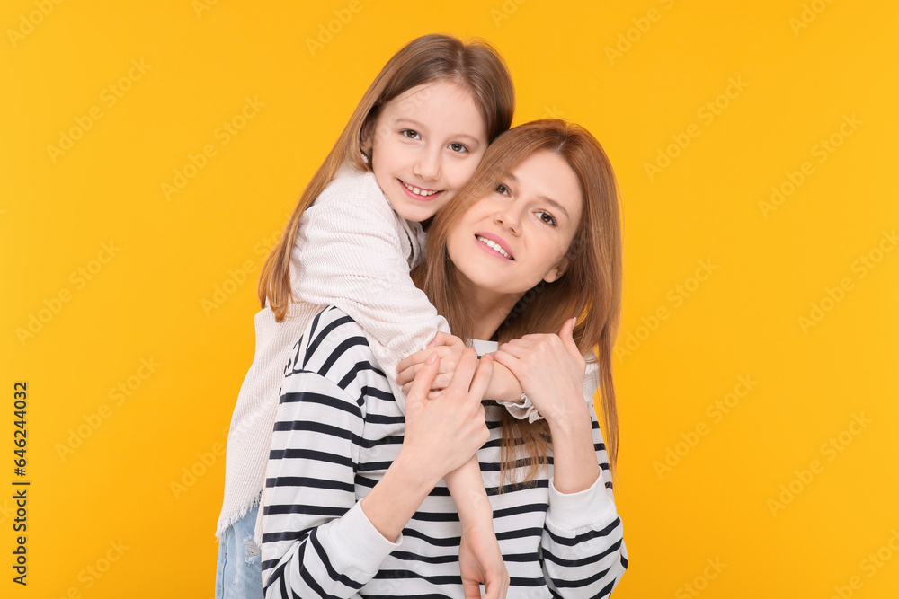 Portrait of happy mother and her cute daughter on orange background Portrait of happy mother and her cute daughter on orange background
