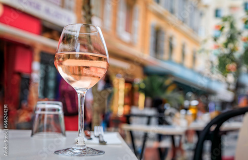 Glass of rose provencal wine at an outdoor restaurant with a background of blurred buildings in Old Town Vieille Ville in Nice, South of France
