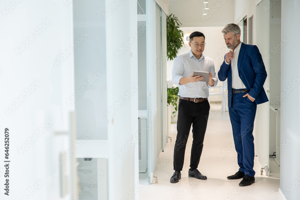 Men standing in corridor in office and talking about their work. Men standing in corridor in office and talking about their work.