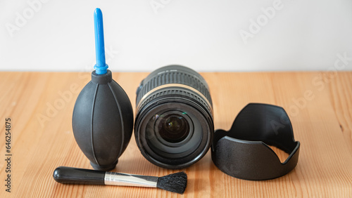 Small modern set kit to clean photo lens with copy space background. Pear blower, objective, brush and lens hood at the wooden table