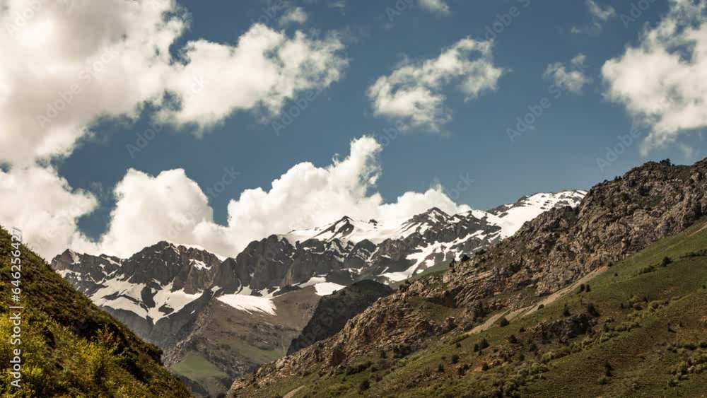 Timelapse mountains. Sunny day in mountain gorge. Inaccessible mountain peaks with remains of snow. Urungach. Blue sky with clouds. Puffy fluffy white clouds. Cumulus cloud scape timelapse. Timelapse mountains. Sunny day in mountain gorge. Inaccessible mountain peaks with remains of snow. Urungach. Blue sky with clouds. Puffy fluffy white clouds. Cumulus cloud scape timelapse.