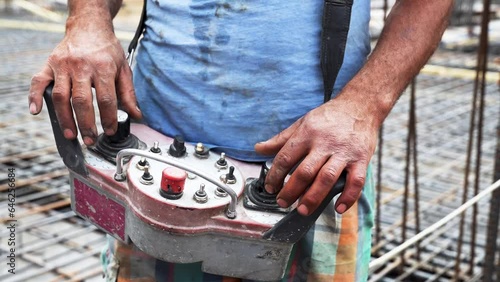 Hands of a construction worker or engineer operating a remote control of construction equipment at a construction site. Close-up view photo