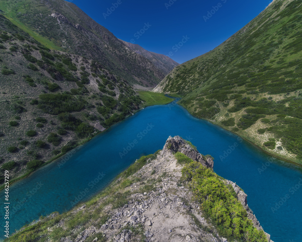 Lake with clear blue water in the mountains under the sky with clouds in summer