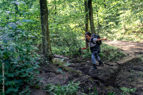 a young mountaineer walks through the forest and crosses a shallow stream
