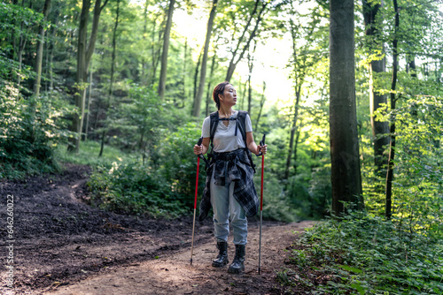 young woman hiking in the forest, using a trail,uses adequate equipment © DusanJelicic