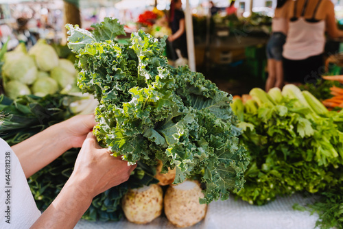 Woman buying fresh green kale vegetable in farmer's market photo