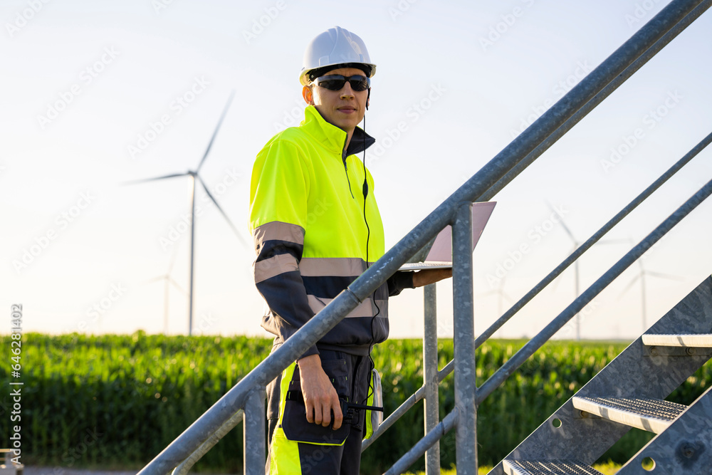 Smiling engineer standing with laptop on staircase Smiling engineer standing with laptop on staircase