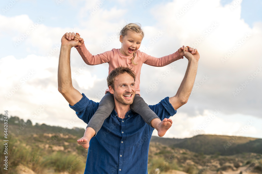 Happy father carrying daughter under cloudy sky Happy father carrying daughter under cloudy sky