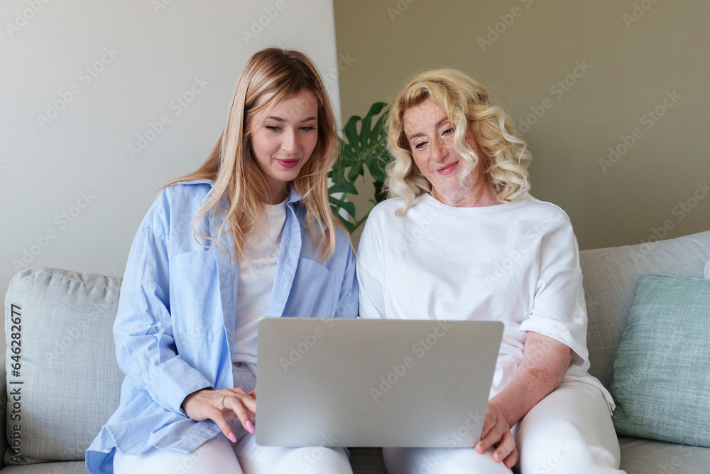 Smiling woman helping mother to use laptop Smiling woman helping mother to use laptop