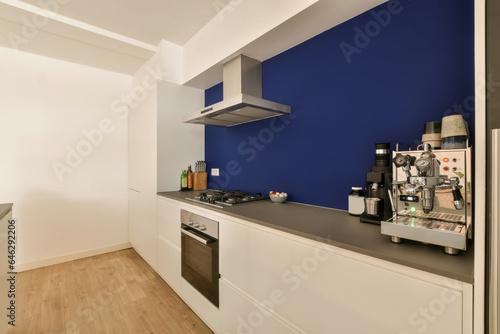 a kitchen area with blue walls and white cupboards on the wall, there is a coffee machine in the corner © Casa imágenes