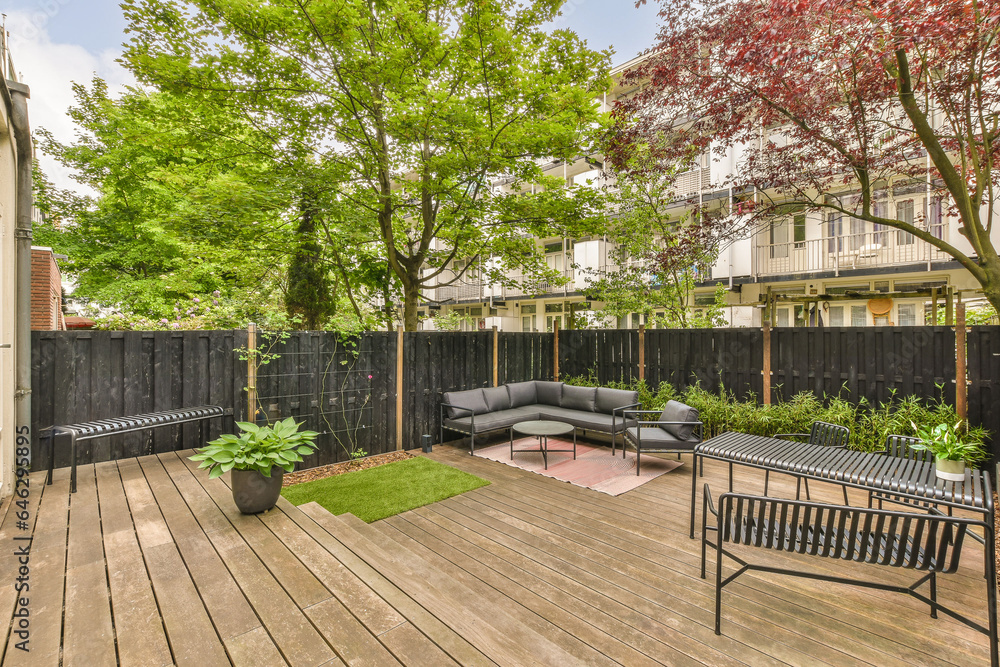 an outdoor living area with wood decking and black privacy fenced in the back yard, surrounded by trees an outdoor living area with wood decking and black privacy fenced in the back yard, surrounded by trees