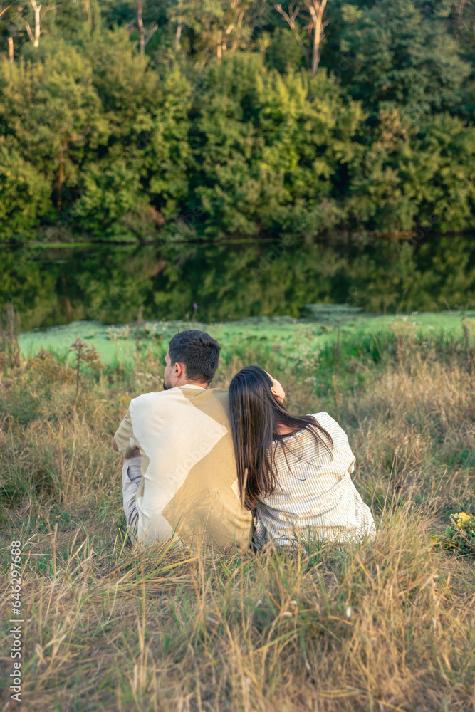 Man and woman sitting by the river on a summer evening, view from the back. Man and woman sitting by the river on a summer evening, view from the back.