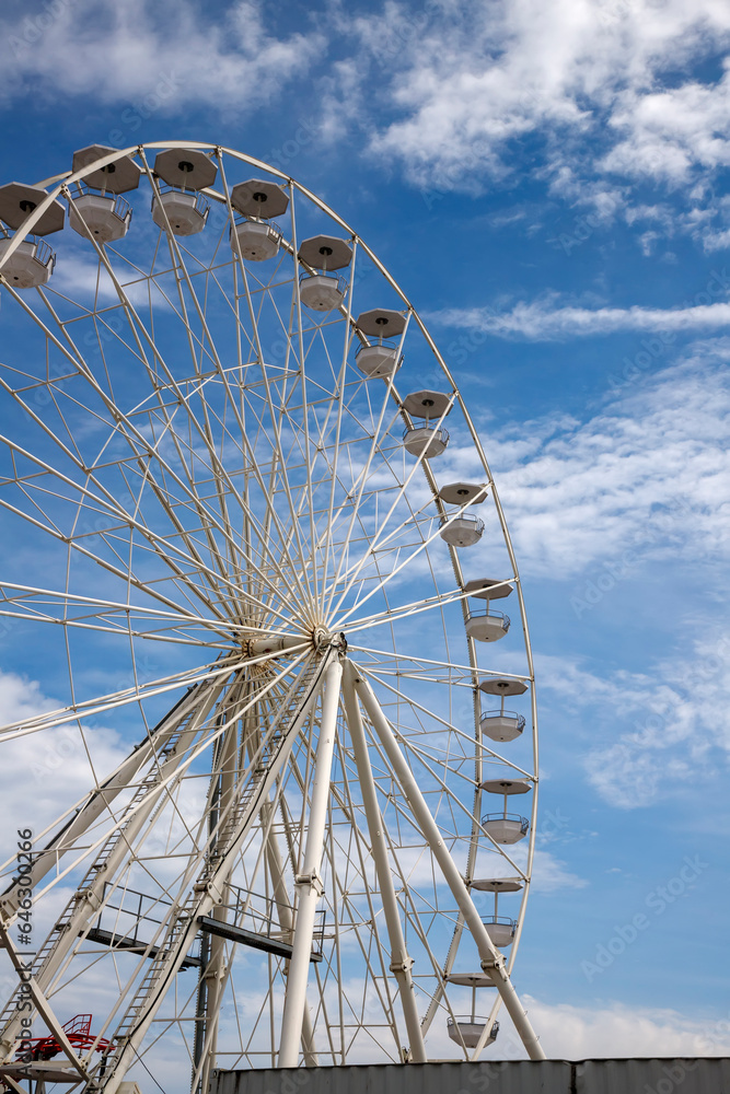 A part of Ferris wheel against a cloudy blue sky A part of Ferris wheel against a cloudy blue sky