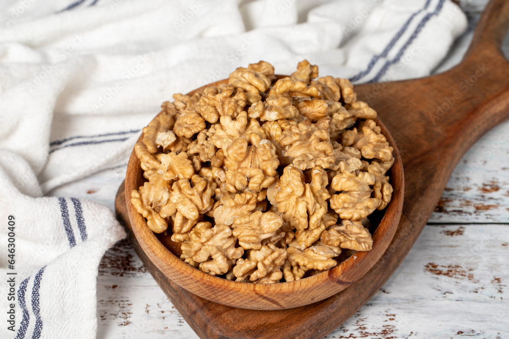 Walnut in wood bowl. Walnut peeled on white wood background Walnut in wood bowl. Walnut peeled on white wood background