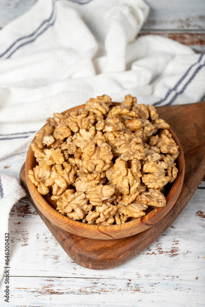 Walnut in wood bowl. Walnut peeled on white wood background. Close up Walnut in wood bowl. Walnut peeled on white wood background. Close up